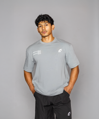 A man dressed in a stone gray shirt that reads "gymryu club," emphasizing strength and performance for dedicated athletes.