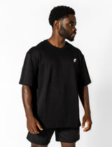 A man in a black t-shirt and shorts, demonstrating the comfortable and versatile design of the Conquer Your Demons Tee.