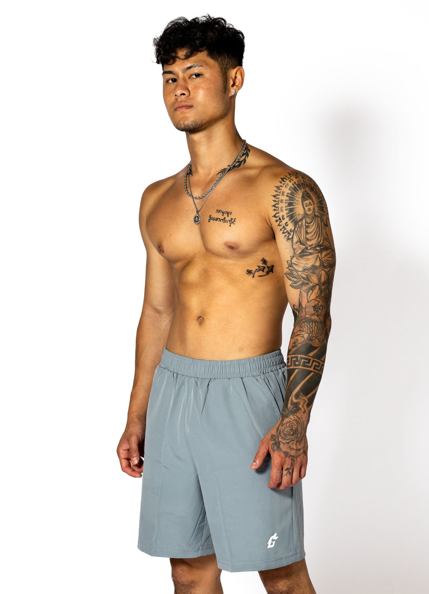 A man with tattoos in stone gray shorts, featuring a streamlined cut and secure pockets for comfort during workouts.