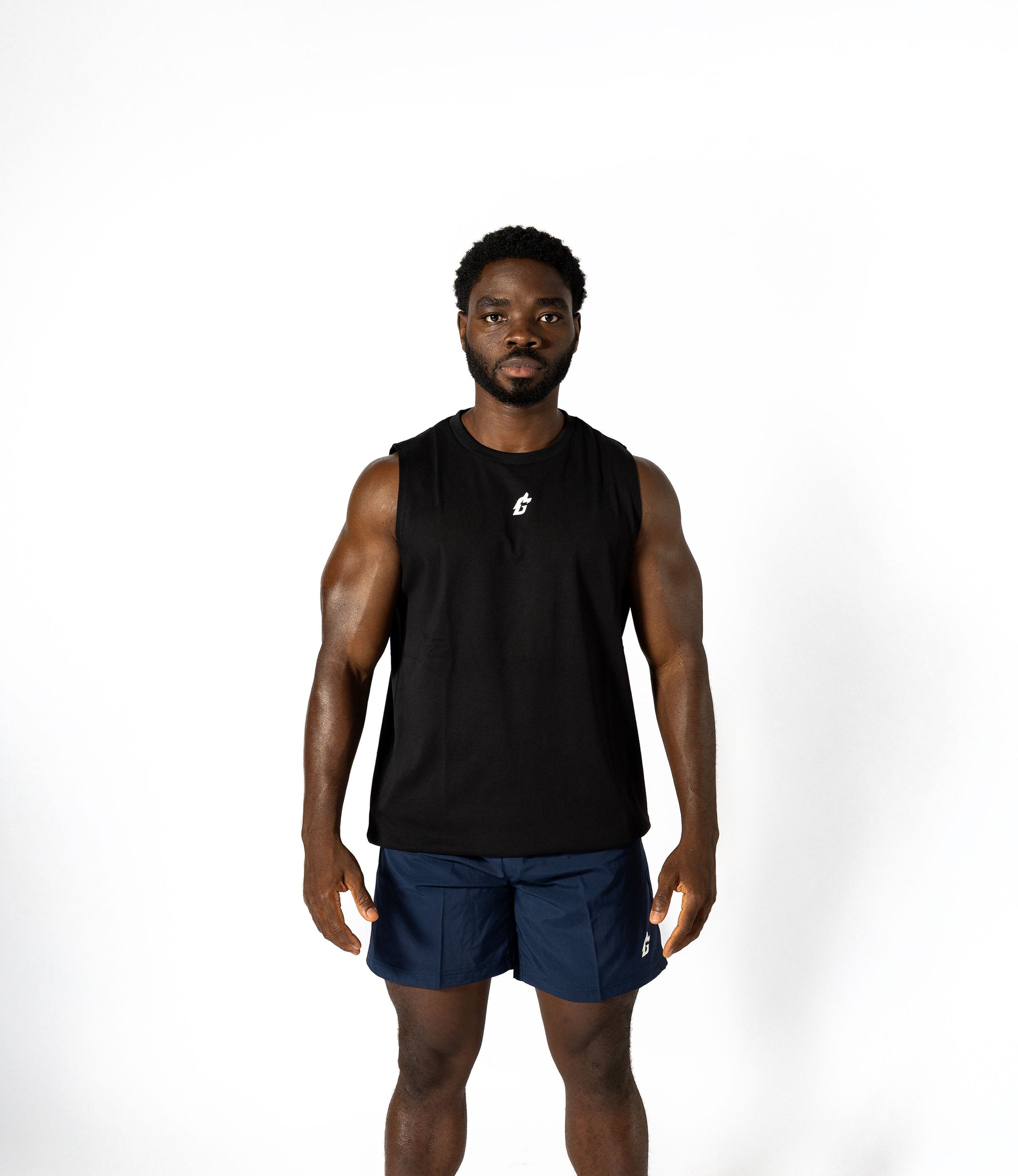 A man in a black tank top and blue shorts, embodying strength and style, prepared for intense lifting sessions.