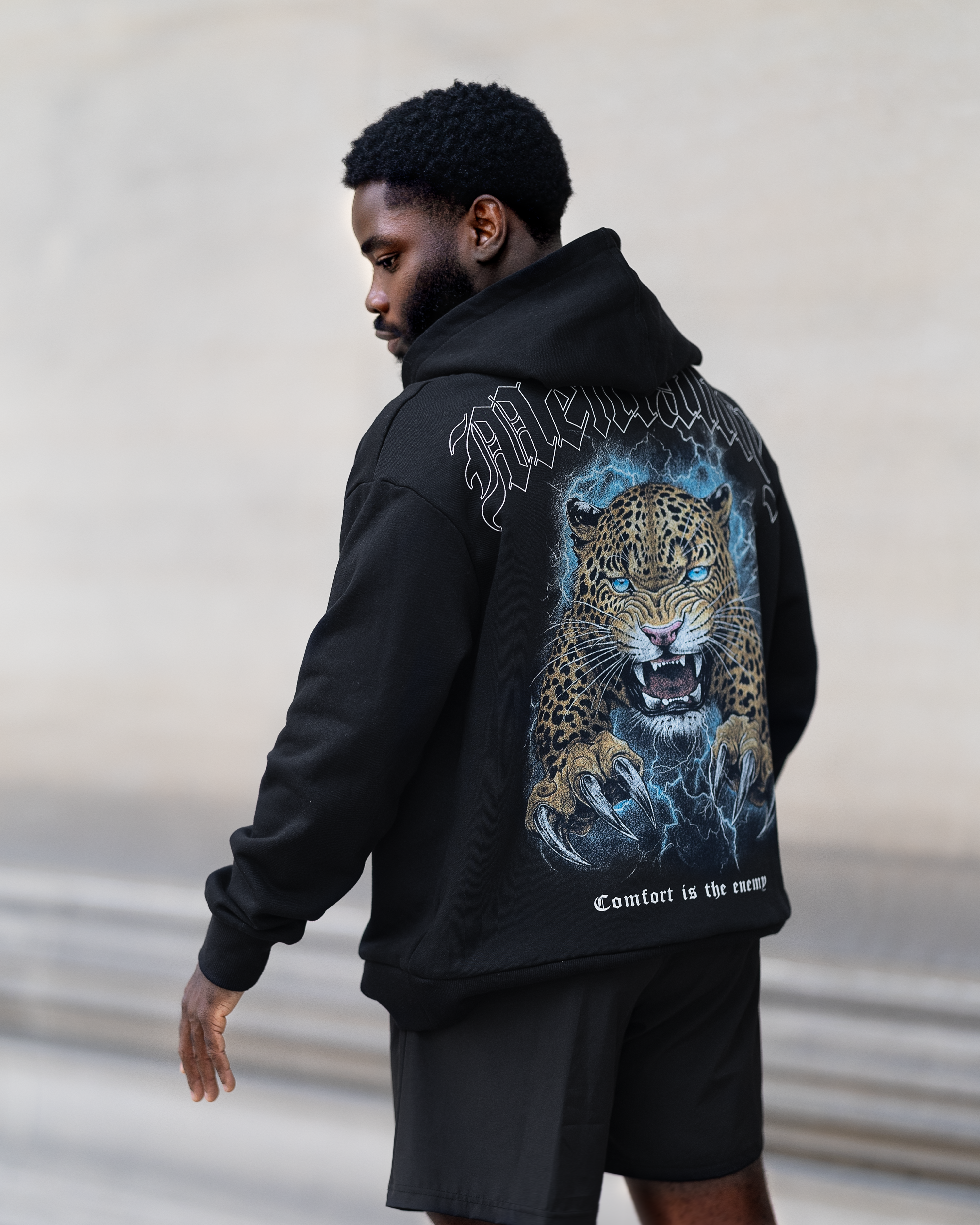 A man in a black hoodie featuring a leopard print, showcasing a stylish and relaxed fit designed for winter activities.