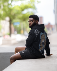 A man in a black hoodie featuring a leopard print, showcasing a stylish and relaxed fit designed for winter activities.